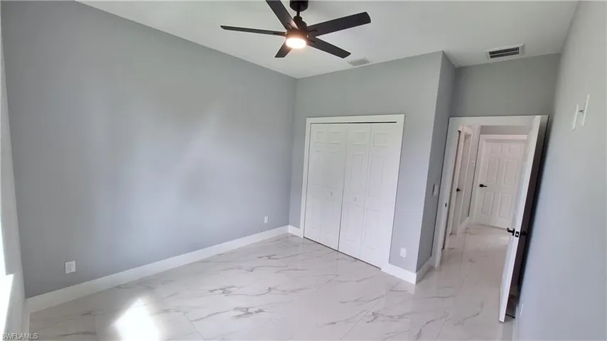 Unfurnished bedroom with a closet, ceiling fan, and light marble finish floors