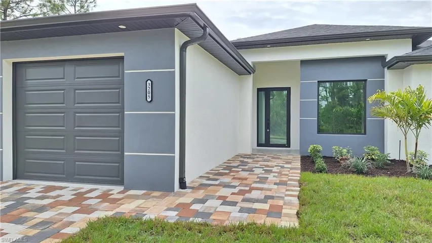 Entrance to property with stucco siding, roof with shingles, and an attached garage