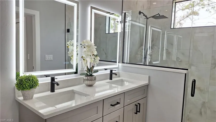 Full bathroom featuring a shower stall and double vanity