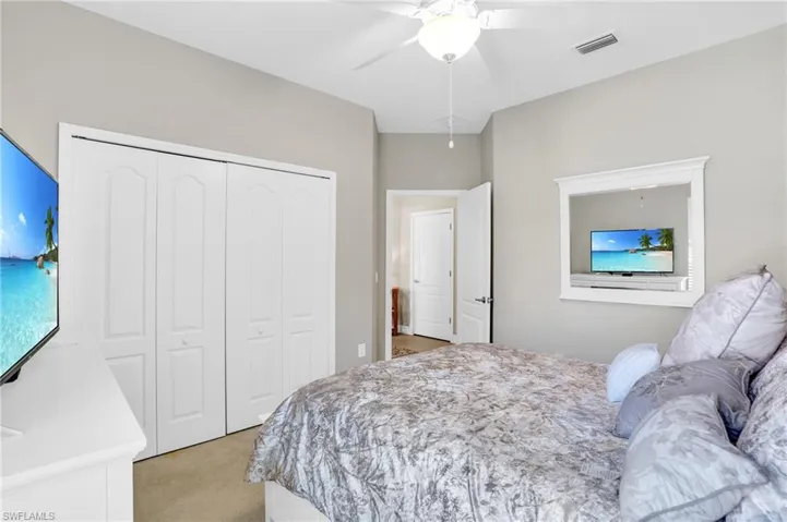 Bedroom with a ceiling fan, visible vents, a closet, and light colored carpet
