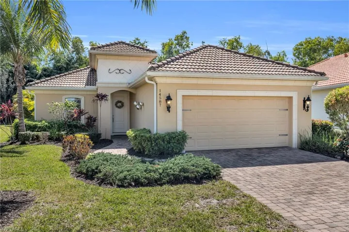 Mediterranean / spanish-style home with an attached garage, a tile roof, decorative driveway, stucco siding, and a front lawn