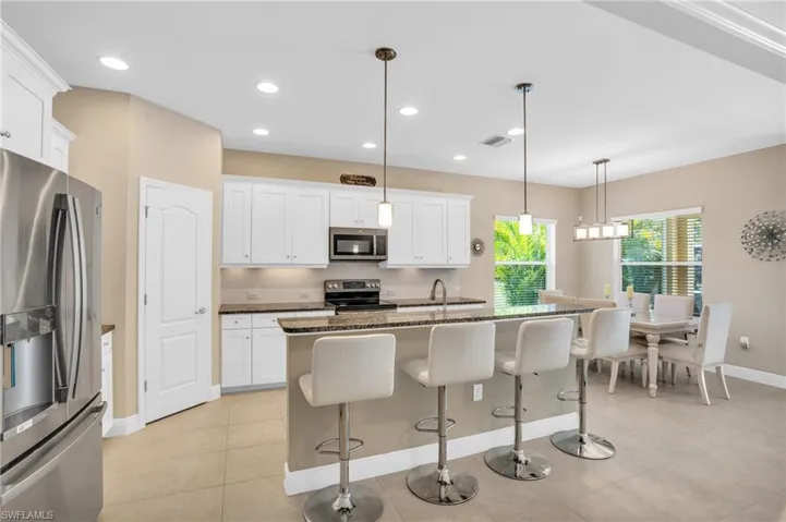 Kitchen with white cabinetry, a breakfast bar area, stainless steel appliances, and dark stone countertops