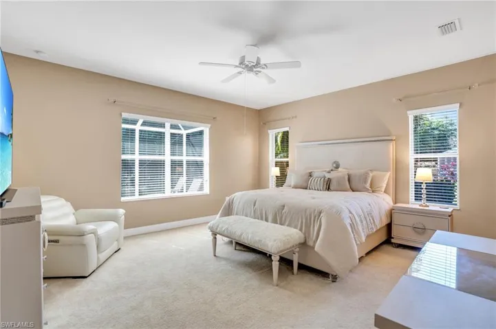 Bedroom with visible vents, ceiling fan, light carpet, and multiple windows