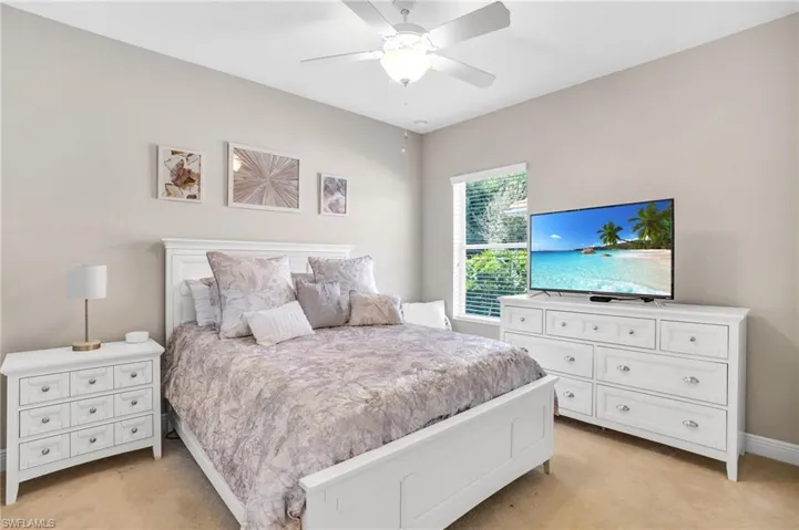Bedroom with light carpet, ceiling fan, and baseboards