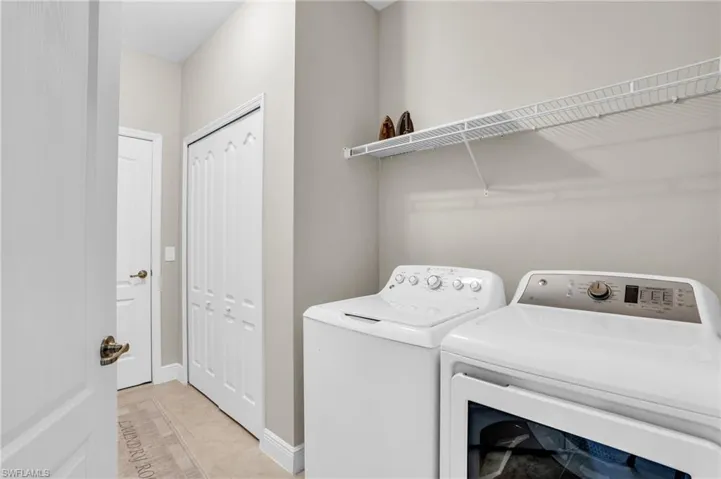 Washroom featuring laundry area, washer and clothes dryer, baseboards, and light tile patterned floors