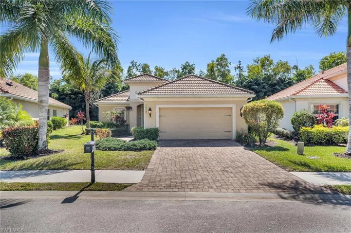 Mediterranean / spanish-style house with decorative driveway, stucco siding, a front yard, a garage, and a tiled roof