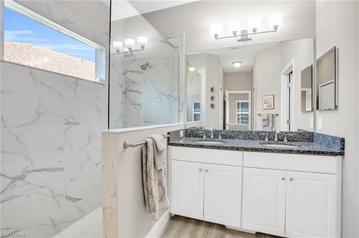 Bathroom featuring a sink, a marble finish shower, and double vanity