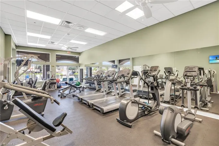 Gym with ceiling fan, a high ceiling, a drop ceiling, and visible vents