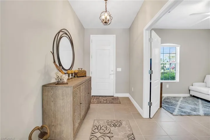 Entrance foyer with baseboards, a notable chandelier, and light tile patterned flooring
