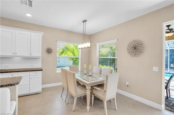 Dining room with light tile patterned floors, baseboards, visible vents, ceiling fan with notable chandelier, and recessed lighting