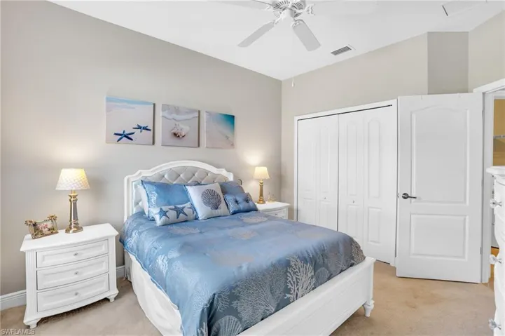 Bedroom with a closet, visible vents, ceiling fan, and light carpet