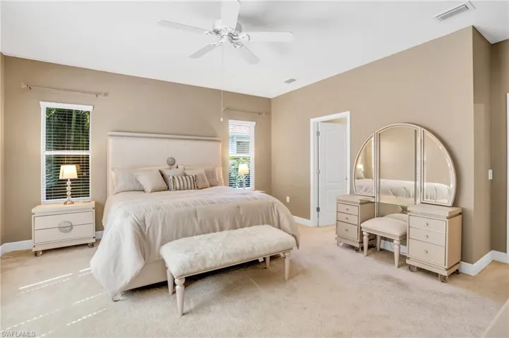 Bedroom with a ceiling fan, visible vents, light carpet, and baseboards
