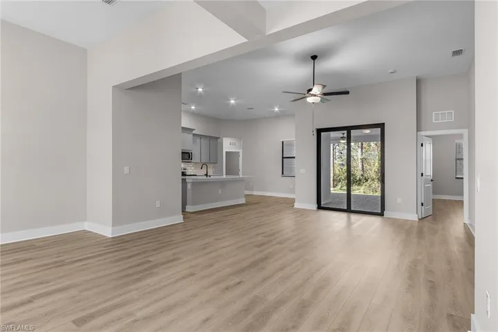 Kitchen featuring appliances with stainless steel finishes, gray cabinets, decorative backsplash, wood tiled floors, and a kitchen island with sink