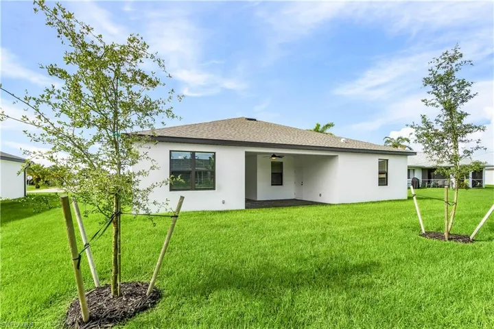 Rear view of property with a lawn, a patio, a ceiling fan, and stucco siding