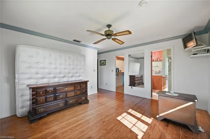 Bedroom with wood finished floors, ceiling fan, and ornamental molding