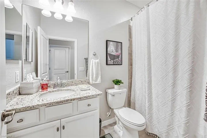 Bathroom featuring a shower with shower curtain, vanity, and a textured wall