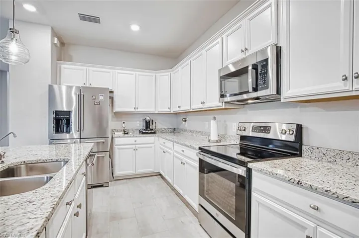 Kitchen featuring stainless steel appliances, white cabinetry, light stone countertops, and hanging light fixtures plus a French door refrigerator