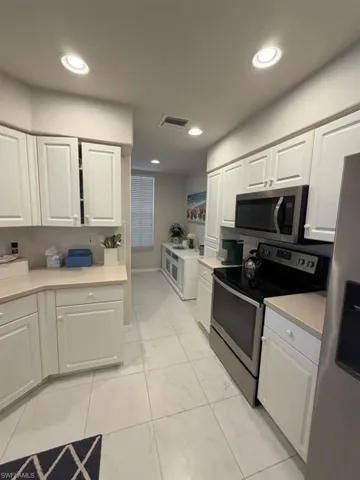 Kitchen with stainless steel appliances, light countertops, white cabinets, and recessed lighting