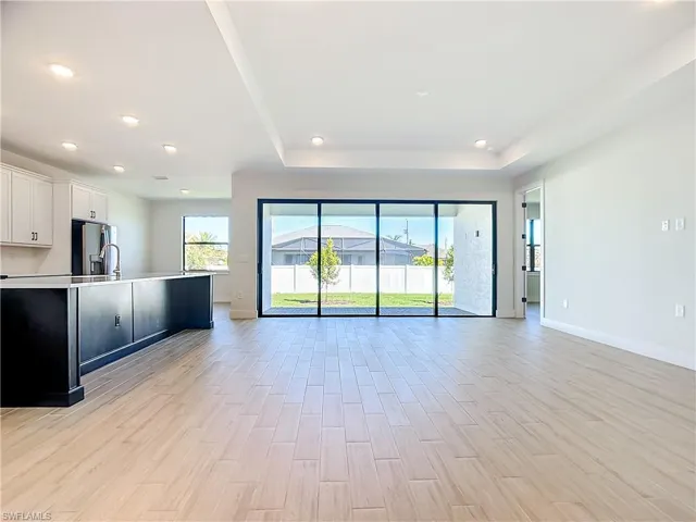 Kitchen with light wood-type flooring, stainless steel fridge, and white cabinetry