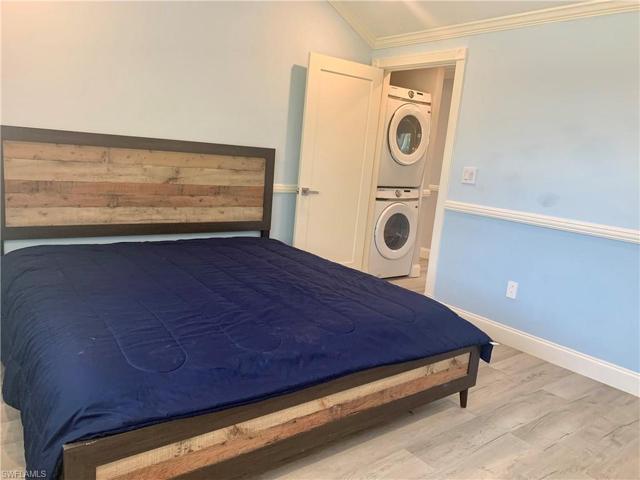 Guest bedroom with shot toward full sized stackable washer/dryer