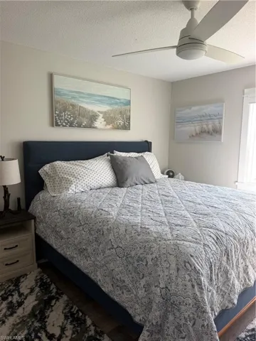Wood-finish flooring with a neutral wall color, contemporary ceiling fan, and built-in window with white trim
