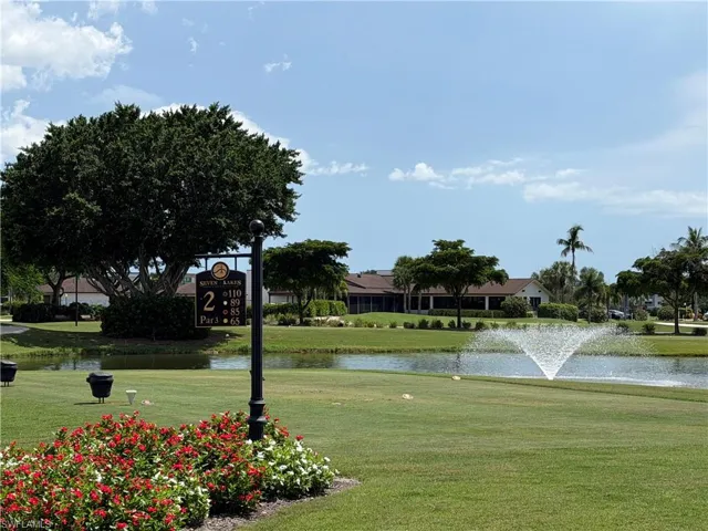 Manicured golf course featuring lush green turf, a decorative fountain, and mature tropical landscaping