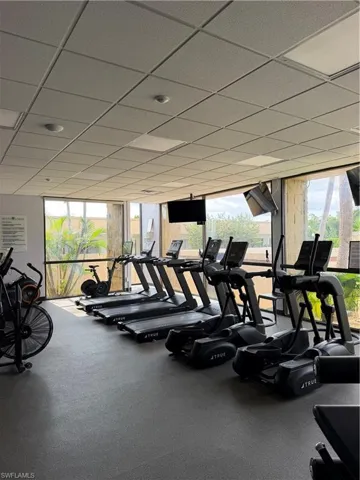 Fitness center with rubber flooring, large windows, and a grid ceiling