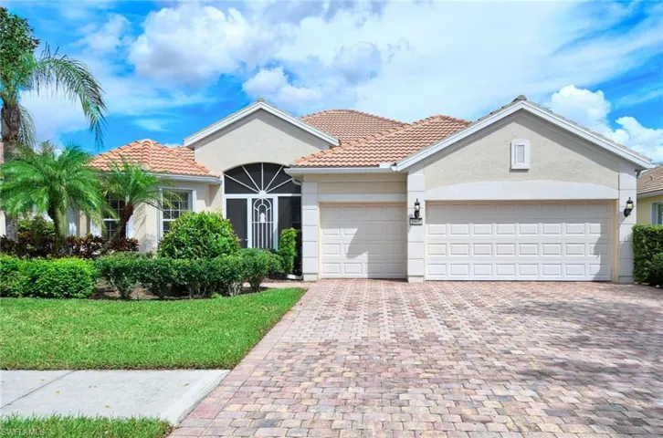 Front of home. 3 car garage. custom screened entry and accordion storm protection