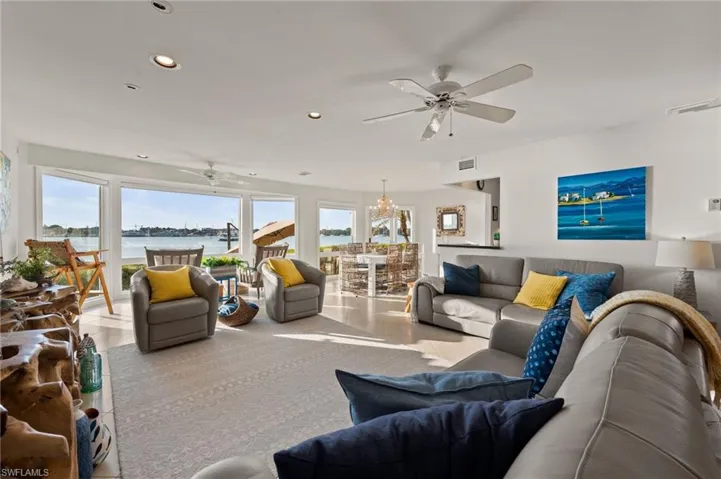 Living room with ceiling fan with notable chandelier and a water view