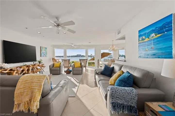 Tiled living room with ceiling fan with notable chandelier