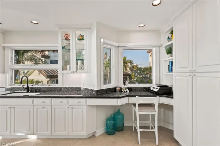 Kitchen featuring light tile patterned flooring, white cabinetry, sink, and dark stone counters