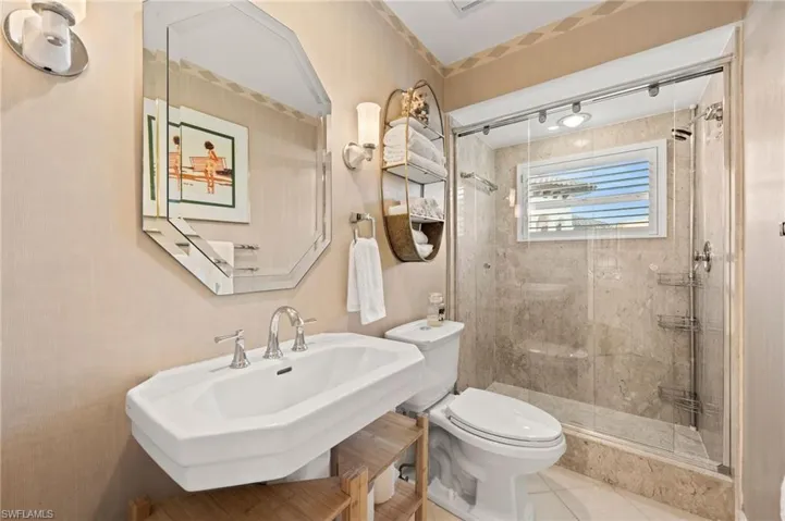 Bathroom featuring sink, tile patterned flooring, a shower with shower door, and toilet