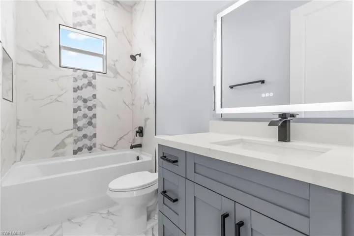 Bathroom with shower / bathtub combination, vanity, and marble finish floors