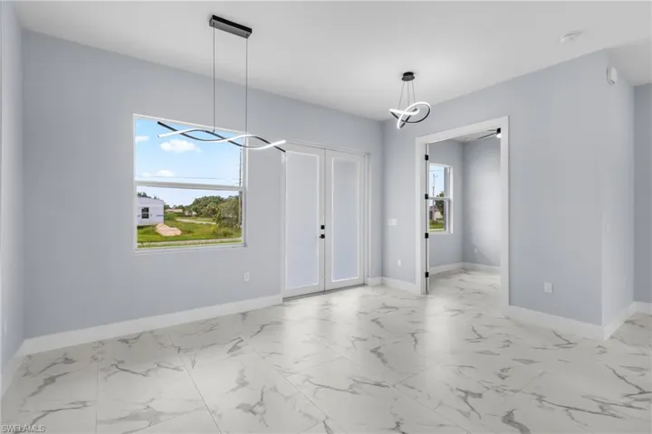 Unfurnished dining area featuring light marble finish floors, a chandelier, and french doors