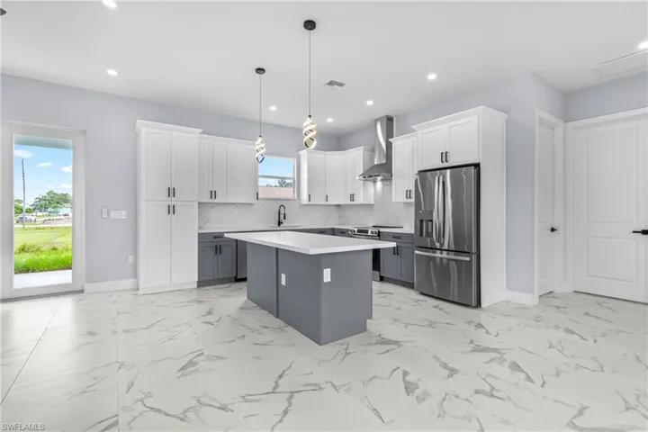 Kitchen featuring gray cabinets, white cabinets, stainless steel appliances, decorative light fixtures, and tasteful backsplash