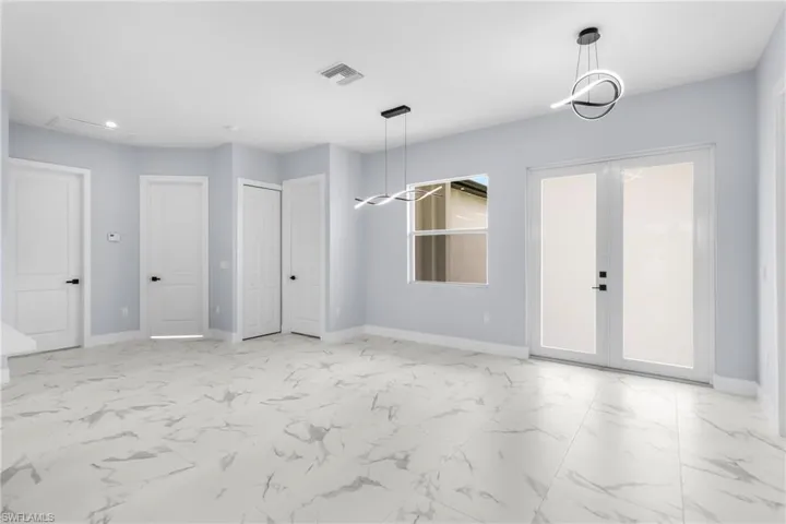 Spare room featuring french doors, light marble finish floors, and recessed lighting