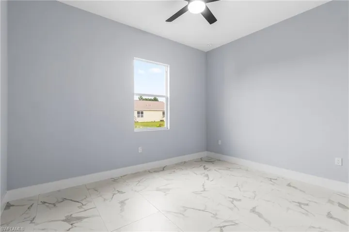 Spare room with marble finish floors and ceiling fan