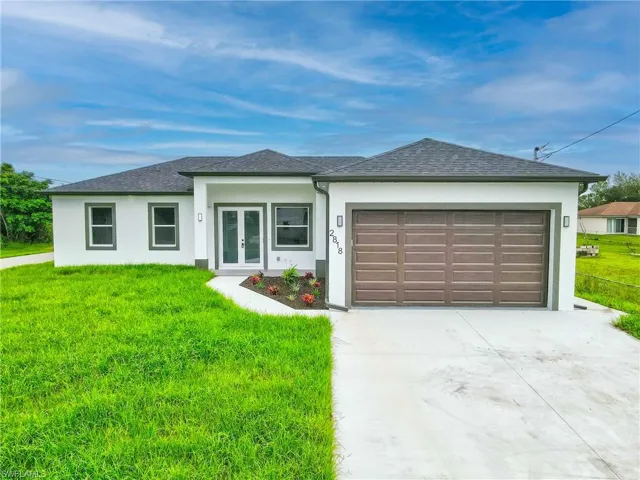 View of front of property with a front lawn, concrete driveway, stucco siding, a garage, and roof with shingles