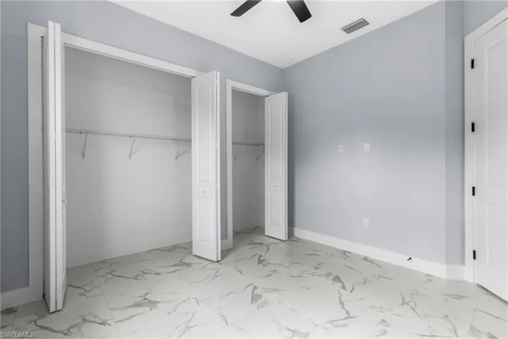 Unfurnished bedroom with a closet, light marble finish floors, and ceiling fan