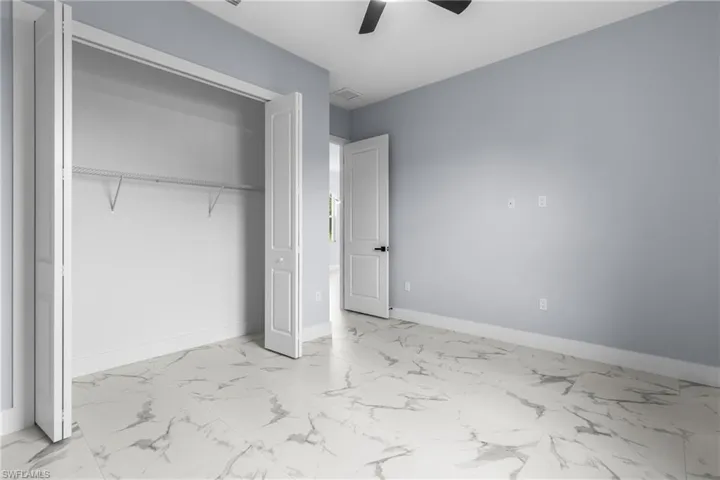 Unfurnished bedroom with light marble finish floors, a ceiling fan, and a closet