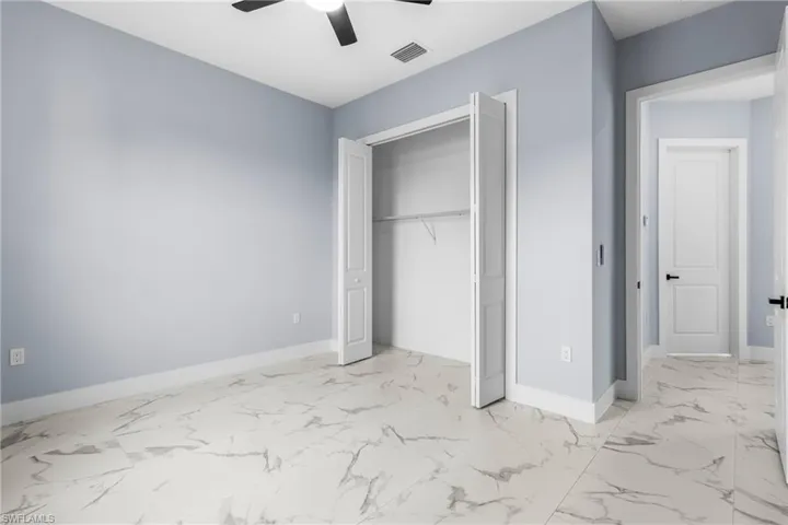 Unfurnished bedroom with light marble finish floors, a closet, and ceiling fan