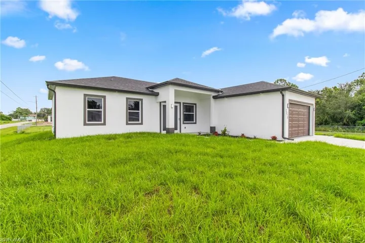 Prairie-style house with a garage, driveway, stucco siding, and a front lawn