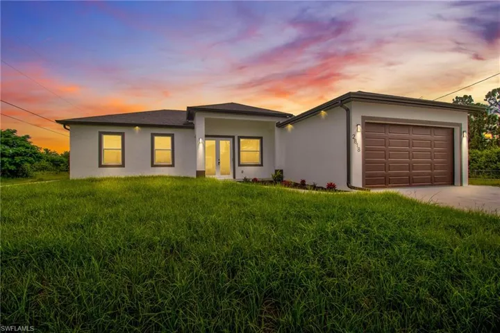 View of front facade with an attached garage, driveway, stucco siding, and a front yard