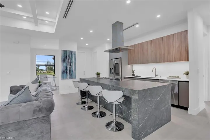Kitchen featuring a breakfast bar area, a kitchen island, stainless steel appliances, island exhaust hood, and sink