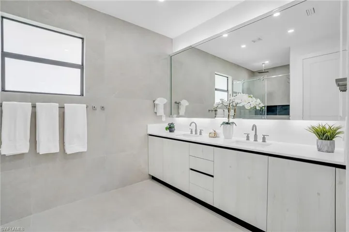Bathroom featuring tile patterned floors, tile walls, and dual bowl vanity