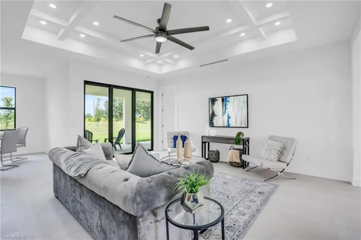 Living room featuring beamed ceiling, ceiling fan, light tile patterned floors, and coffered ceiling