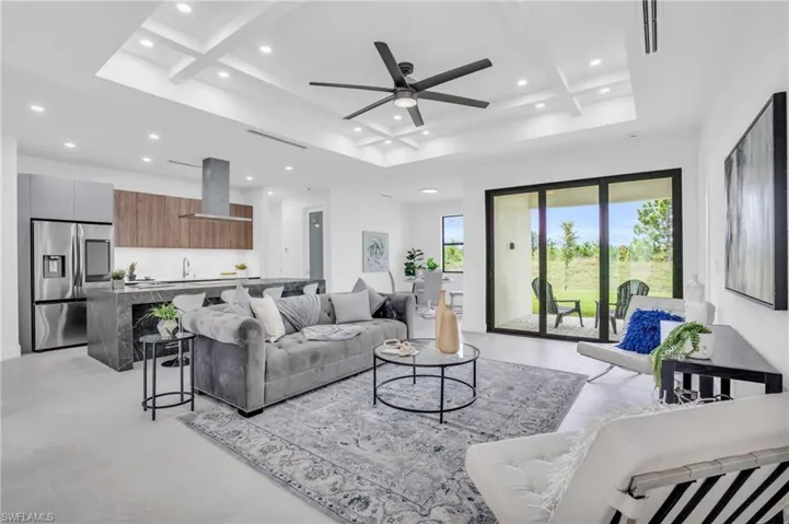 Tiled living room with beamed ceiling, ceiling fan, and coffered ceiling