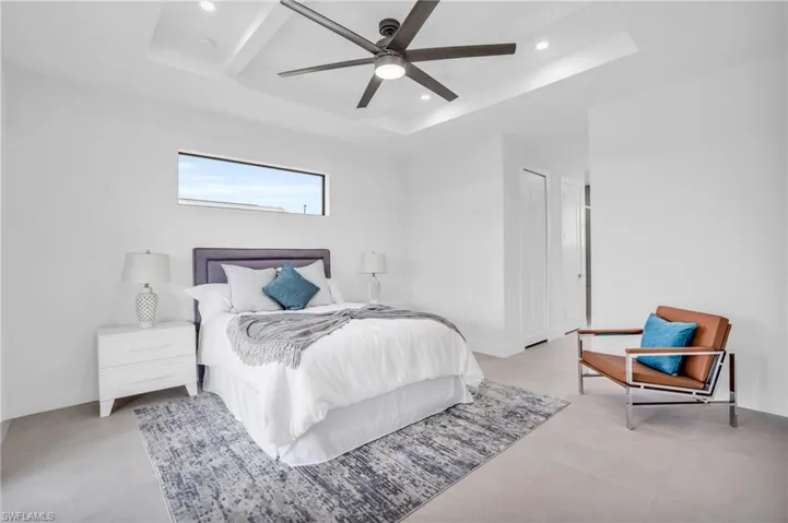 Bedroom featuring a raised ceiling, light colored carpet, and ceiling fan
