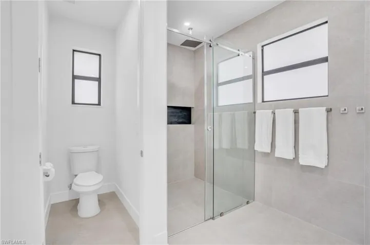 Bathroom featuring a shower with shower door, tile patterned floors, and toilet