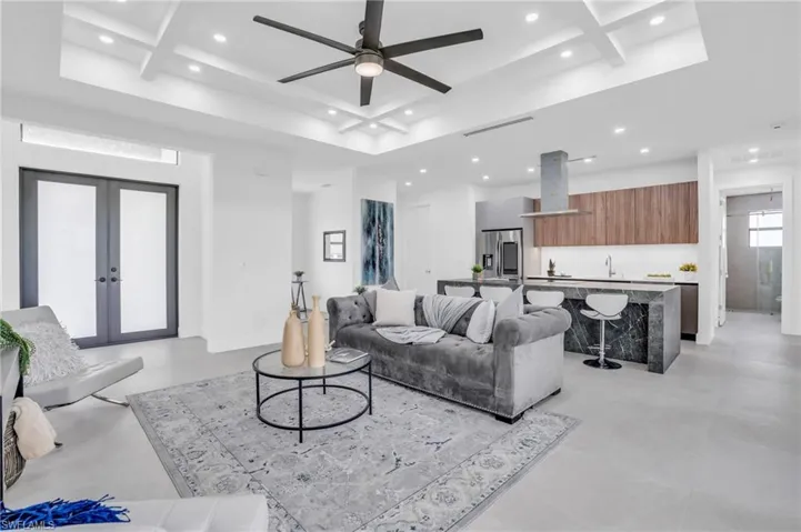Tiled living room featuring beamed ceiling, french doors, ceiling fan, and coffered ceiling